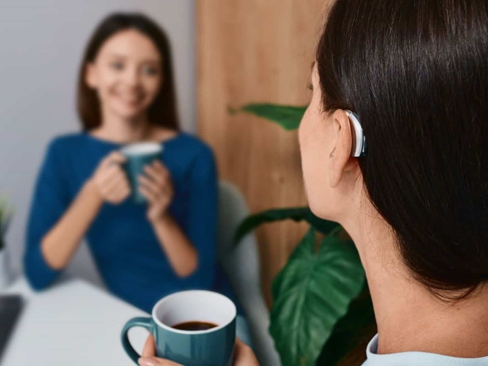 Woman wearing a receiver-in-canal hearing aid during a conversation — hearing aid styles fitted at Better Hearing Clinic in McAllen, TX