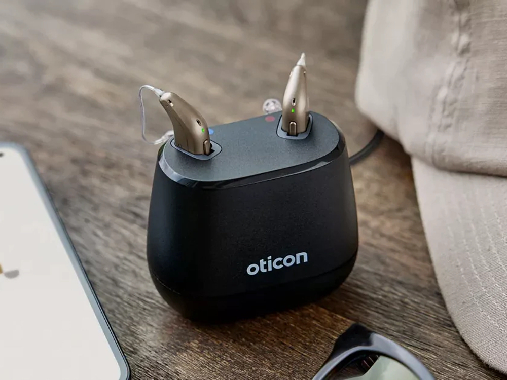 Rechargeable hearing aids charging in a dock — an alternative to disposable batteries available at Better Hearing Clinic in McAllen, TX